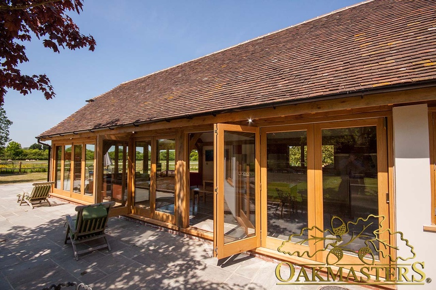 Exterior of modern garden room kitchen with open glazed bi-fold patio doors 