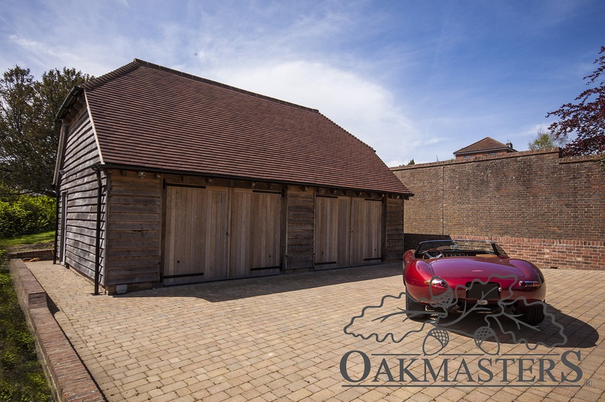 Two-bay oak framed garage set at the end of a paved driveway