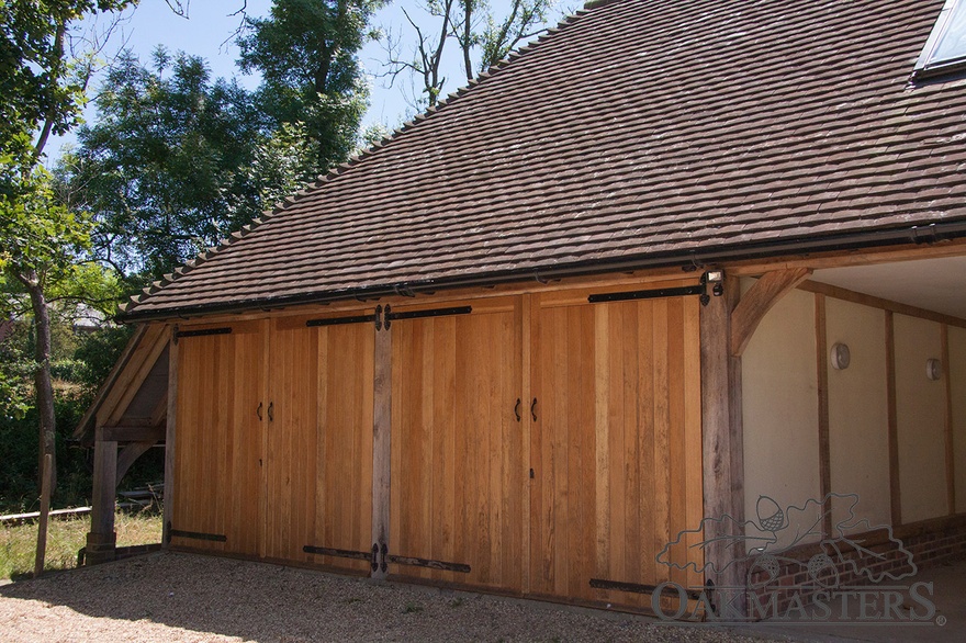 Two of the bays are enclosed with handmade oak garage doors
