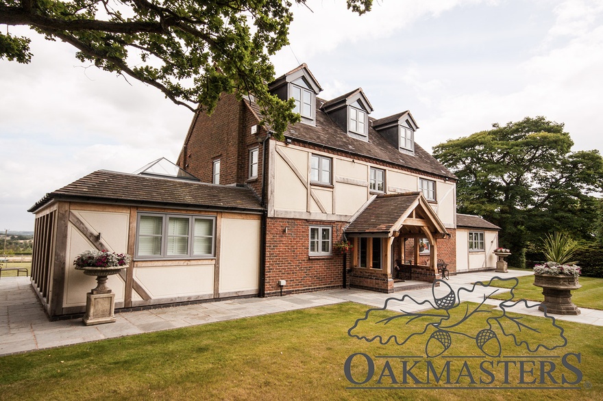 Traditional oak cladding and an oak porch add character to the front of the brick house