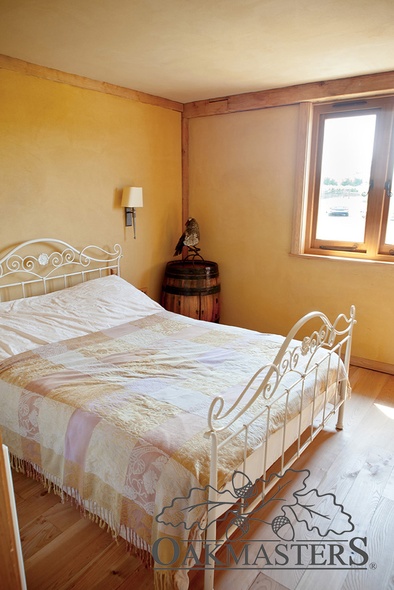 Spare bedroom with visible oak frame and earthy coloured walls