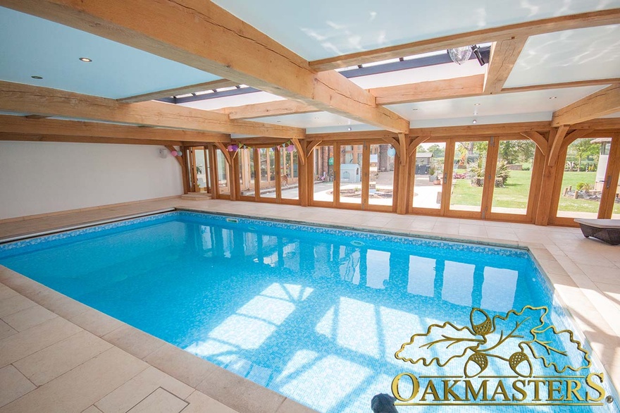 Large glazed lantern on the flat oak ceiling allows the light t flow inside the oak pool house