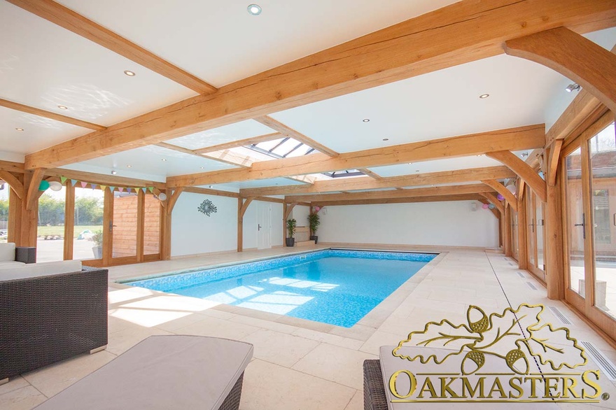 The flat roof of the oak framed pool house features glazed lanterns